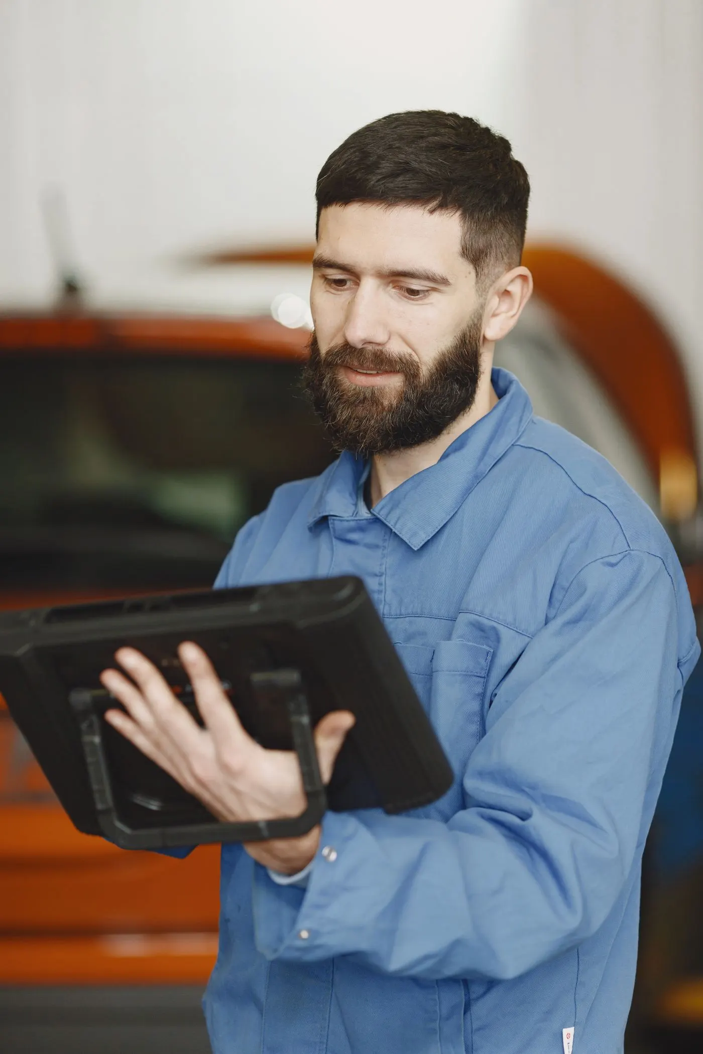 Handwerker in Arbeitskleidung schaut zufrieden auf ein Tablet